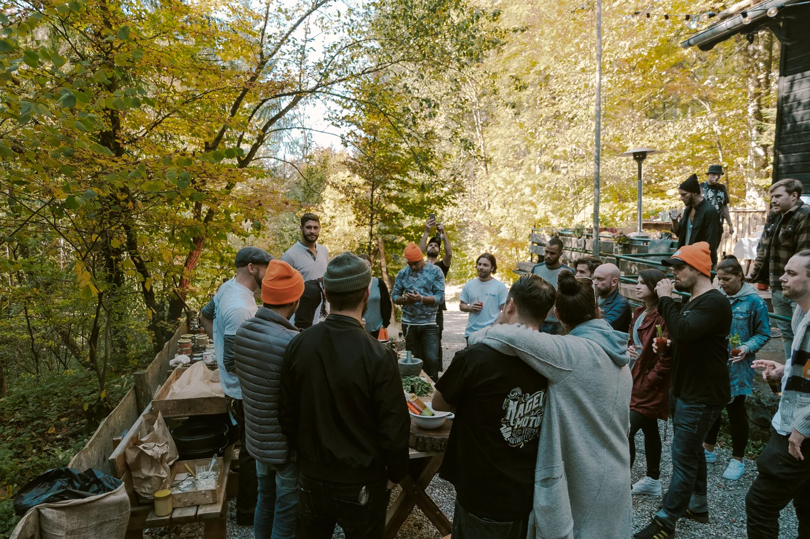 Bulleit Indian Summer BBQ 2017 bei Projekt Draussen — Gruppe im Herbstwald rund um das Cateringbuffet vor dem Holzhaus